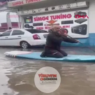 Adana’da etkili olan yağış sonrası sanayi esnafı caddede sörf tahtalarıyla ilerledi