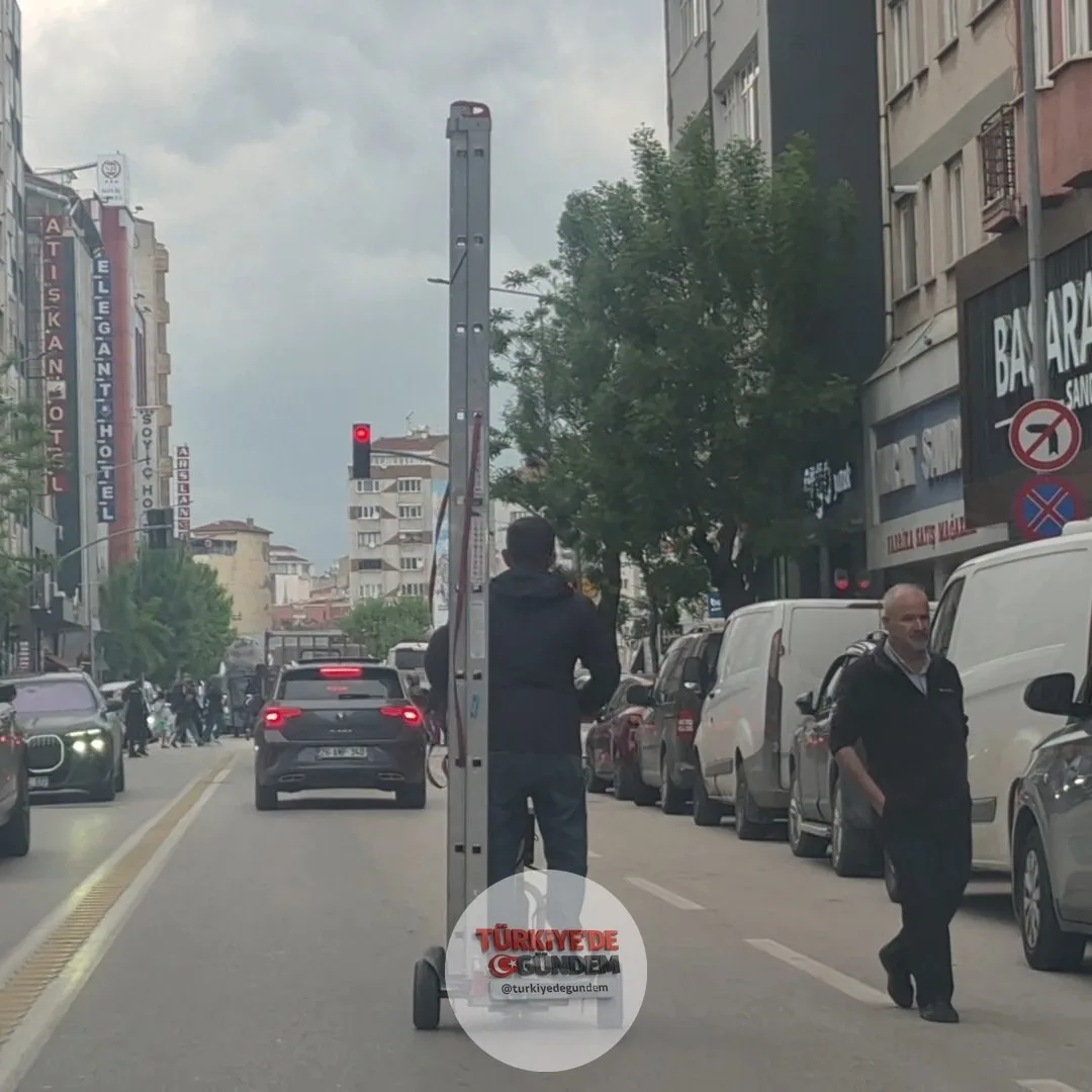 Eskişehir'de bir vatandaş, trafikte elektrikli scooter üzerinde kendisinden uzun bir merdiveni taşıdı.