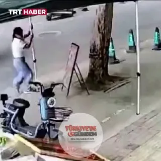 Çin’de etkili olan tayfunda bir kişi, tutunduğu tenteyle birlikte savrulurken sökülen bir ağacın altında kalmaktan son anda kurtuldu